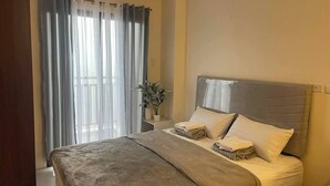 Een hotelkamer met een bed, een nachtkastje met een plant en een raam met gordijnen.