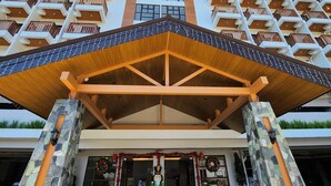 Een meerlaags hotel met een opvallende geometrische gevel, een overdekte ingang en stenen pilaren.