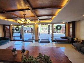 Un hall d’hôtel avec un plafond en bois, deux canapés, un comptoir d’accueil et un lustre.