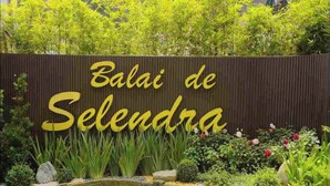 Een bord met de tekst 'Balai de Selendra', omringd door weelderige begroeiing en een klein vijvertje.
