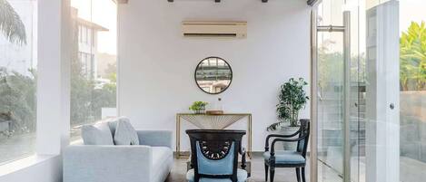 Un salon moderne avec un canapé, deux fauteuils, un miroir rond et une petite table.