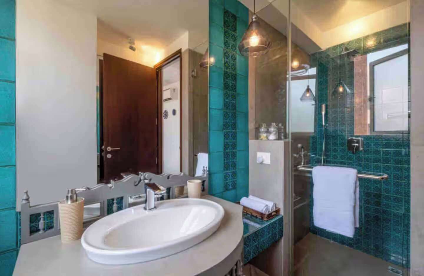 A modern bathroom with a large sink, a glass shower enclosure, and a mirror.