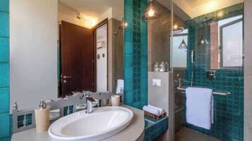 A modern bathroom with a large sink, a glass shower enclosure, and a mirror.