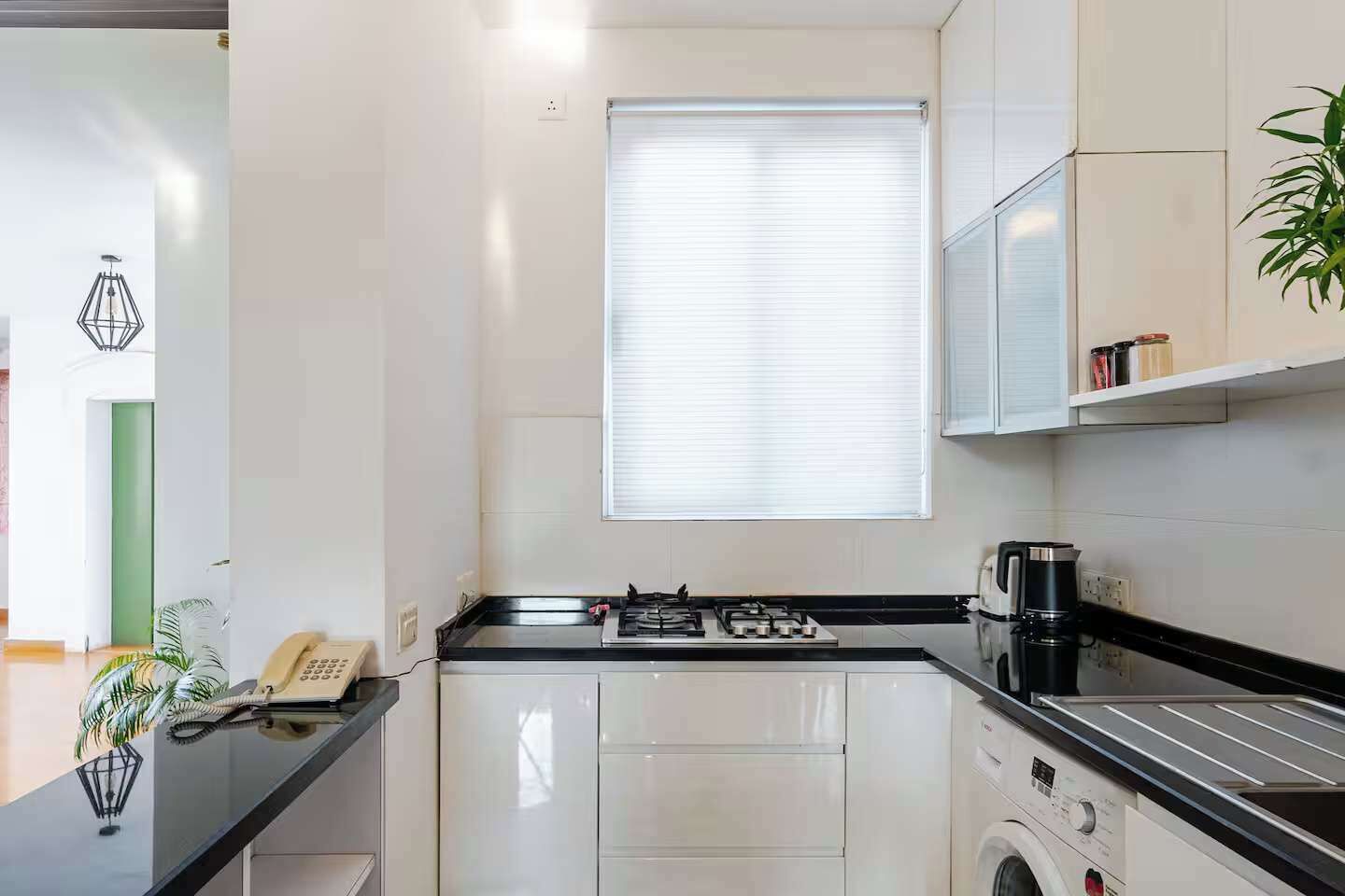 A modern kitchen with white cabinetry, a gas stove, a coffee maker, and a washing machine.