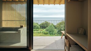 Een moderne kamer met een grote schuifglazen deur die uitkomt op een balkon met uitzicht op zee.
