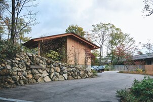 A stone wall with a wooden structure, a paved road, and parked cars.