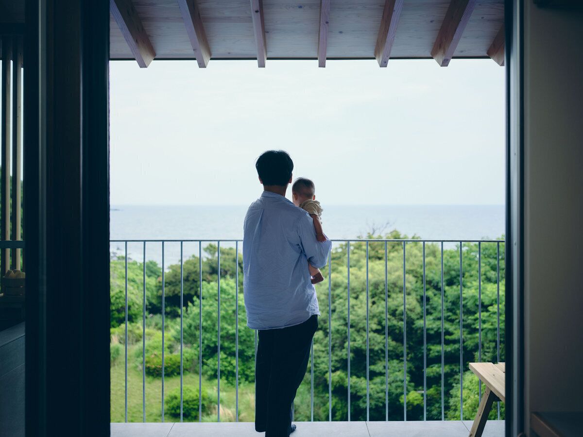 A balcony with a view of the sea and greenery.