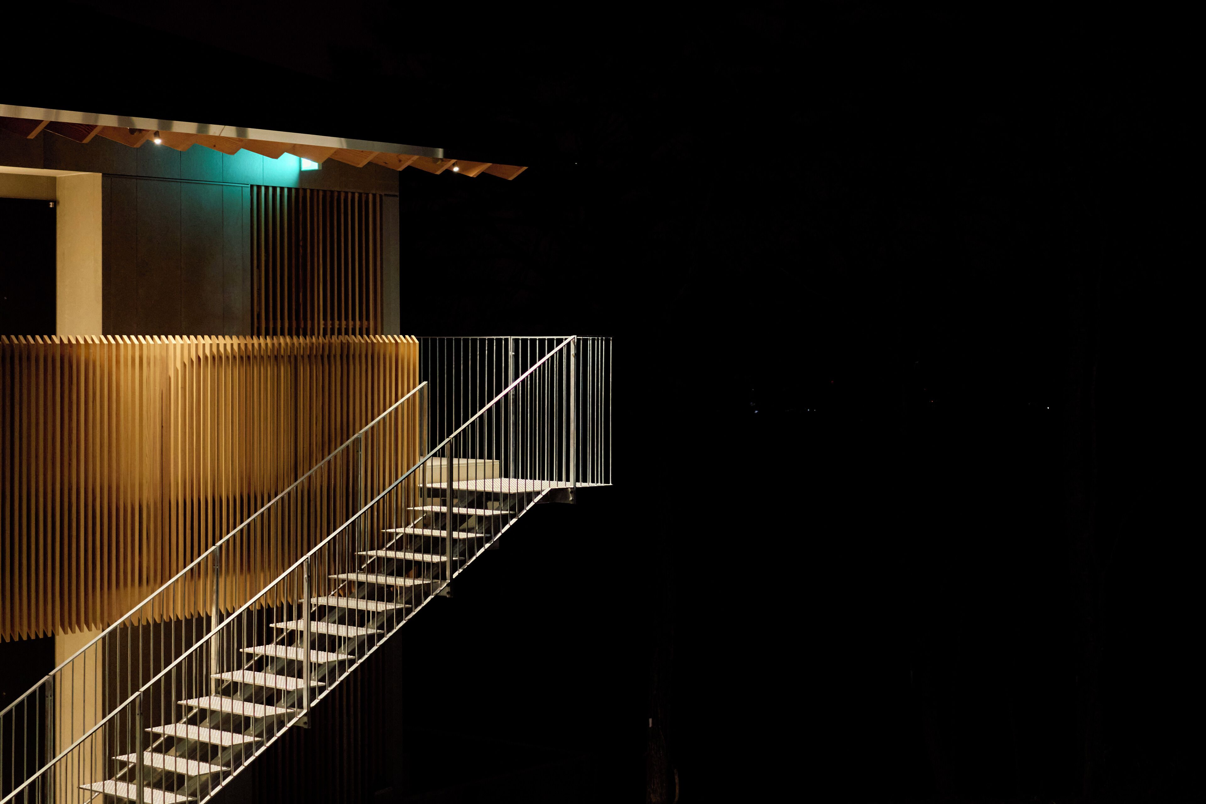 A modern staircase with metal railings and wooden paneling, leading to an upper level.