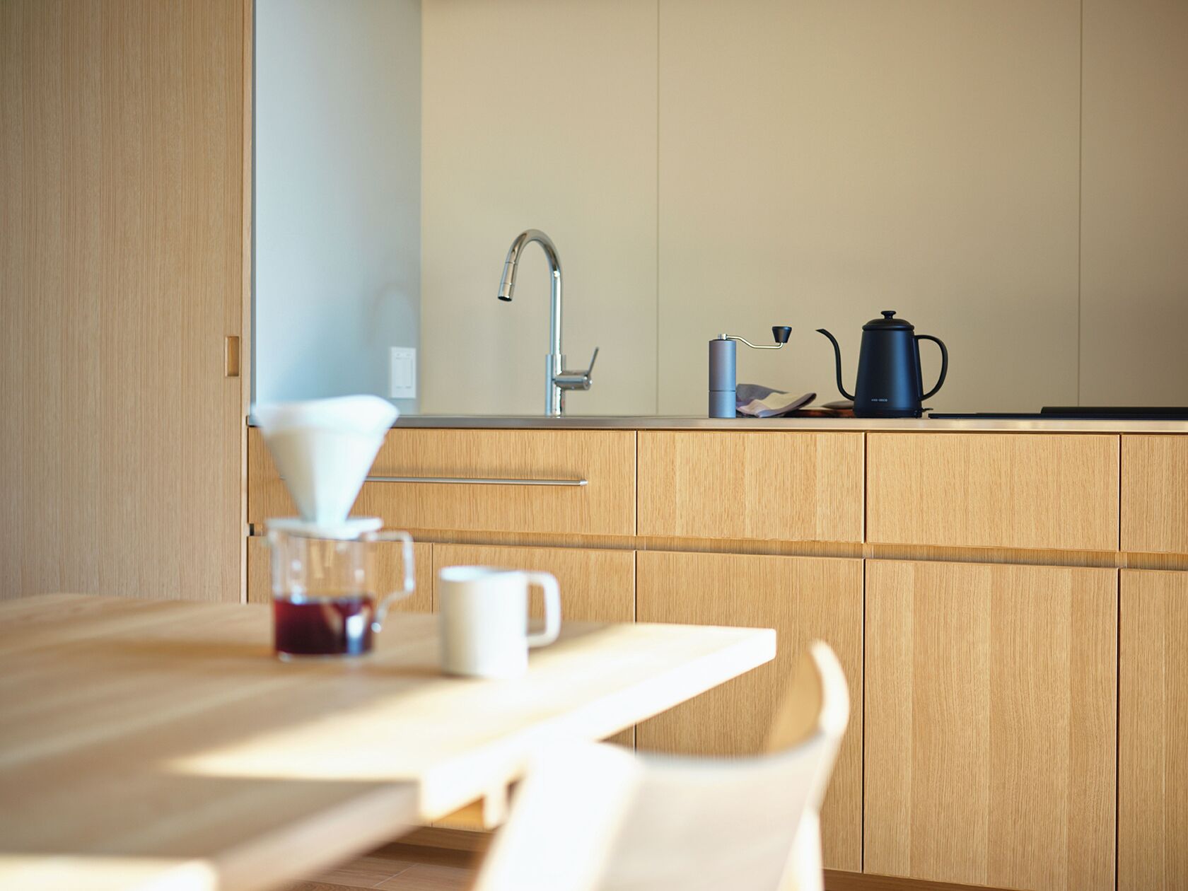 A modern kitchen with wooden cabinets, a stainless steel sink, and a coffee maker on the counter.