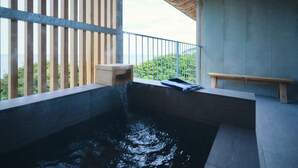 Uma banheira de hidromassagem com um banco de madeira e guarda-corpo de madeira, com vista para uma paisagem verde.