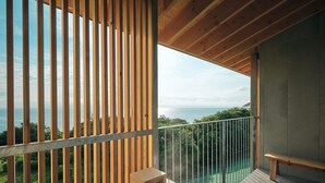 Een balkon met een houten hekwerk, een bankje en uitzicht op de oceaan.