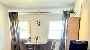 Una sala moderna con comedor, televisor de pantalla plana y un cartel de bienvenida.