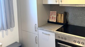 Una cocina compacta con refrigerador, horno y un letrero que dice 'Let's Eat' sobre la encimera.