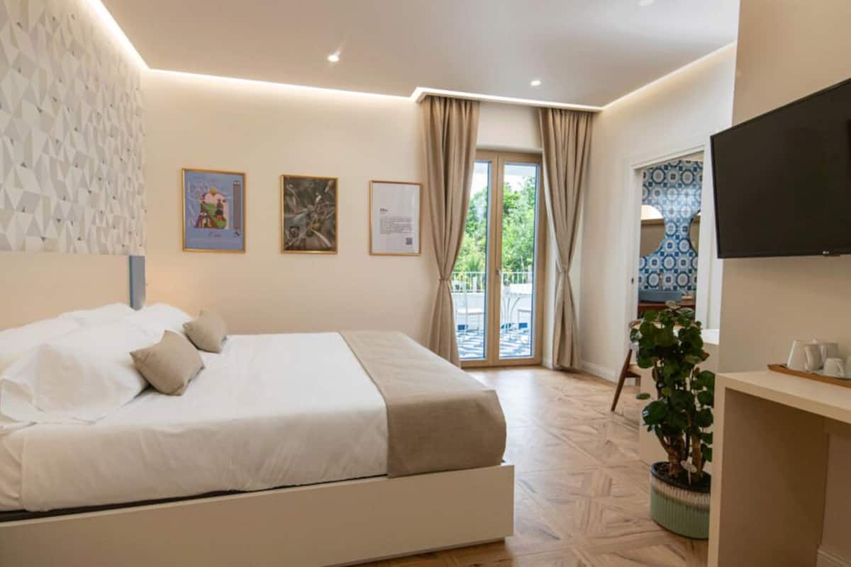Une chambre moderne dotée d’un grand lit, d’un téléviseur à écran plat et d’un balcon offrant une vue sur l’extérieur.