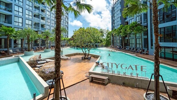 A pool area with lounge chairs and palm trees, surrounded by high-rise buildings. - Rooftop Pool Gym 600 m to Beach C161 (Kamala)