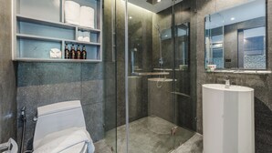 A modern bathroom with a glass-enclosed shower, a white sink, and shelves with toiletries. - Rooftop Pool Gym 600 m to Beach C161 (Kamala)