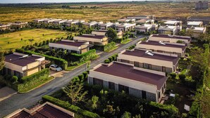 Un quartier résidentiel avec des maisons modernes, une rue principale et de nombreux espaces verts environnants.