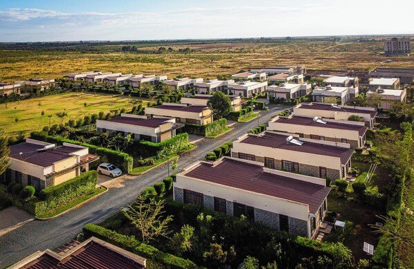 A residential area with modern houses, a main road, and surrounding greenery.