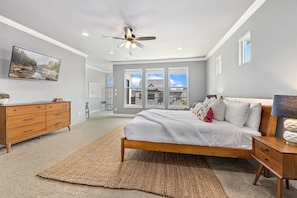 A bedroom with a bed, a dresser, a ceiling fan, a large window, and a view of the outside. - Passage - Arts District - Garage - 0.5 mi DT (Bentonville)