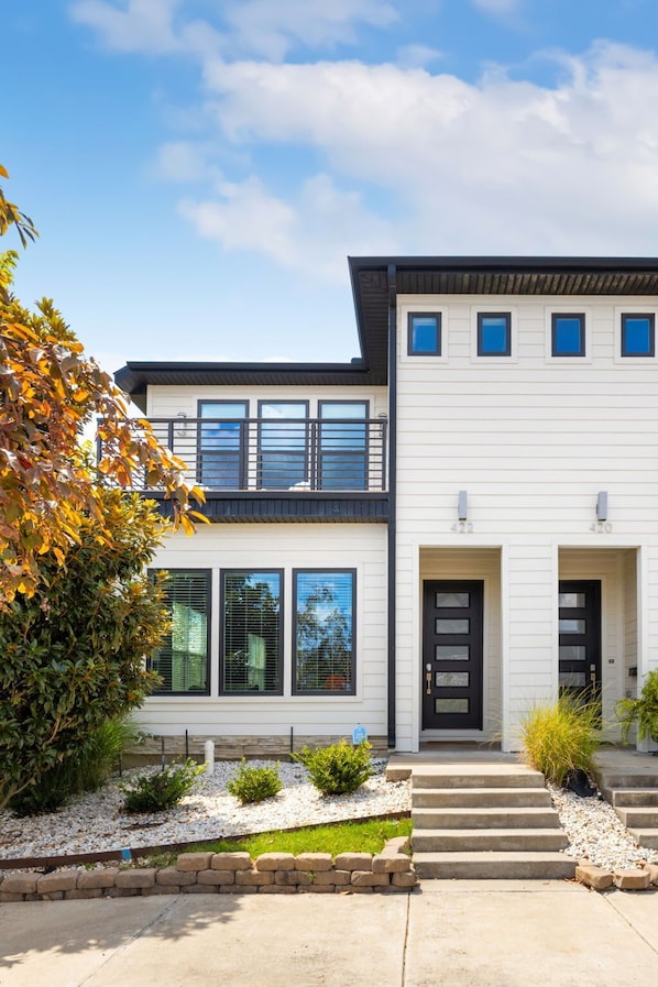A modern two-story house with a balcony, large windows, and a well-maintained front yard. - Passage - Arts District - Garage - 0.5 mi DT (Bentonville)