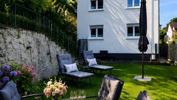 A patio with a table set for two, surrounded by chairs, and a large umbrella.