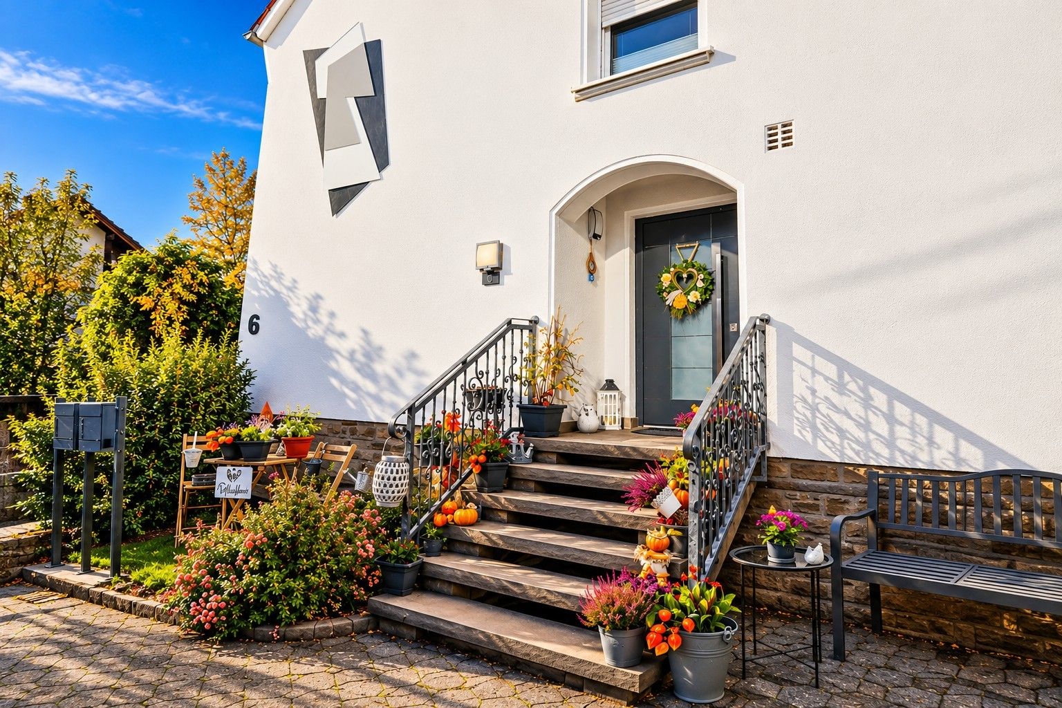 Ein Haus mit weißer Fassade, einer schwarzen Haustür und einer Treppe, die zum Eingang führt.
