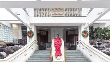 Una majestuosa escalera con un arreglo floral en la parte superior, que conduce a un vestíbulo de techos altos y diseño moderno.