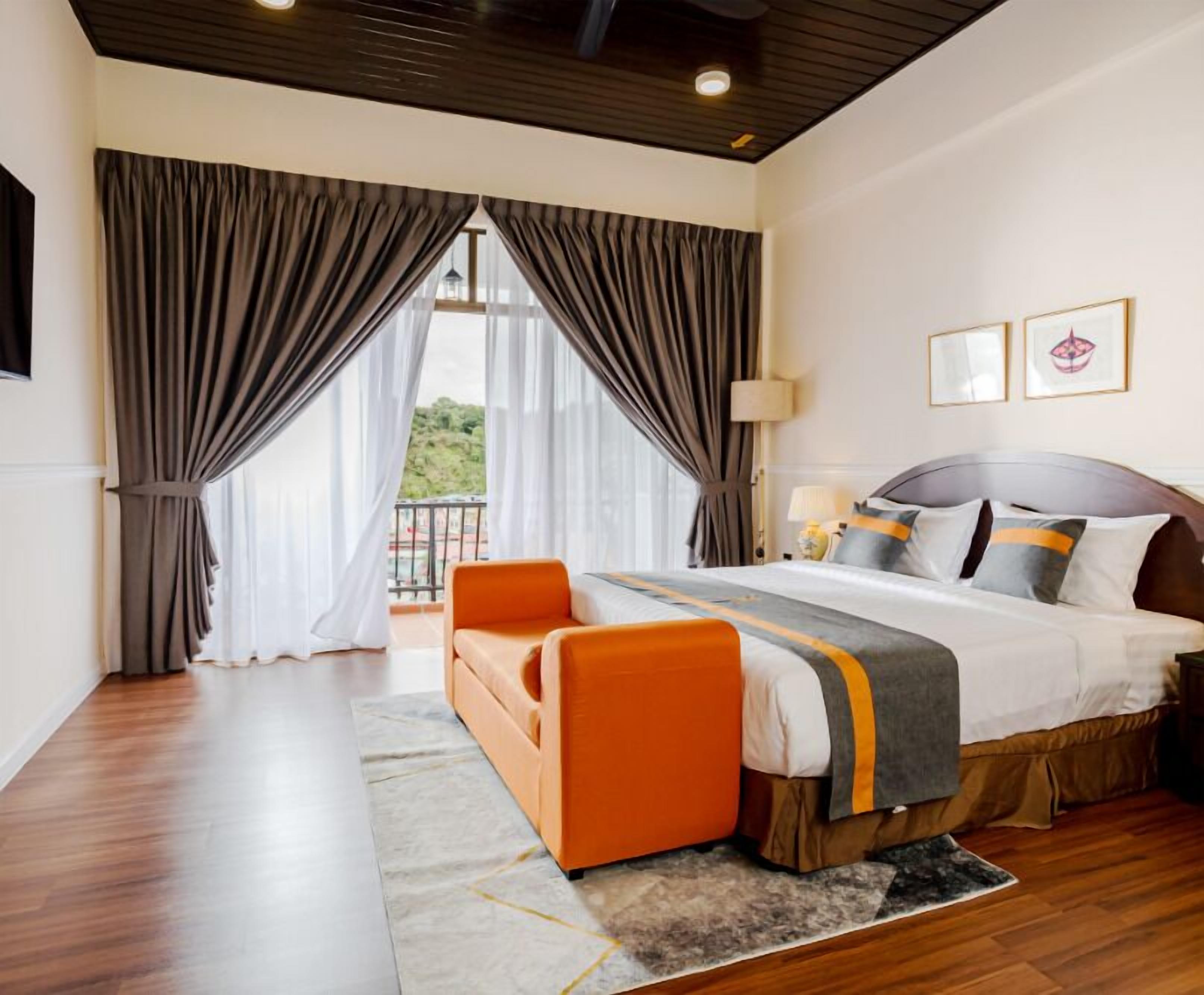 Quarto de hotel com cama grande, sofá e vista para o exterior.