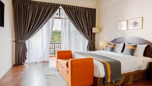 A hotel room with a large bed, an orange sofa, a view of greenery outside, and a balcony. - SpringHill Resort (Brinchang)