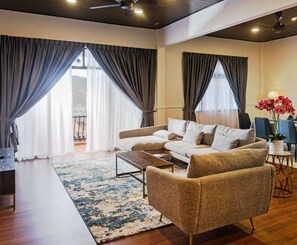 A modern living room with a sofa set, a coffee table, and a view of the outdoors through large windows.