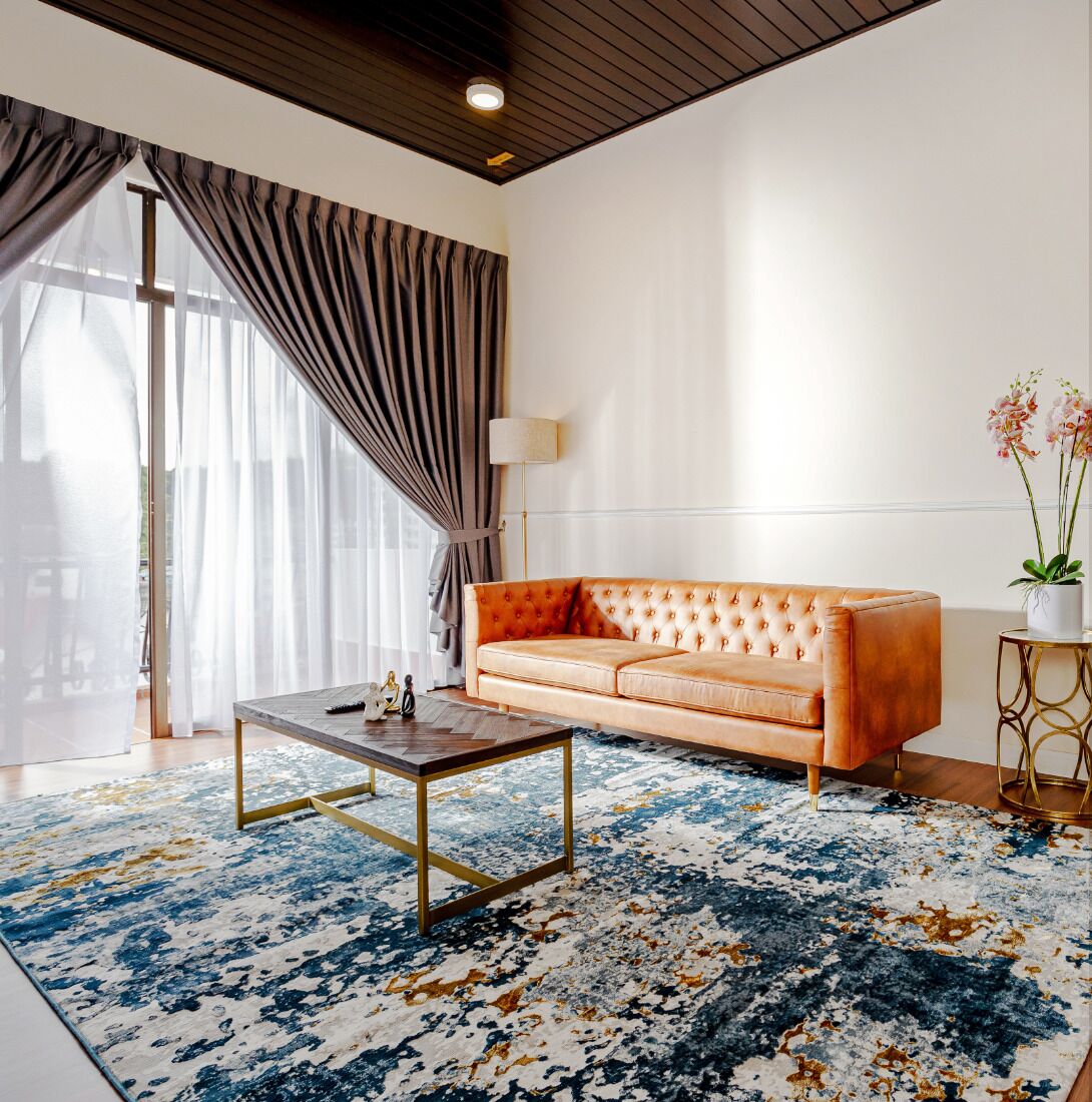 Una sala moderna con un sofá de cuero, una mesa de centro y una alfombra estampada.