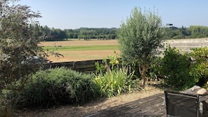 A view from a balcony overlooking a garden with various plants and a field in the background. - T2 30 M² 4 Sleeps max close to shops and 4-way access (Guignen)