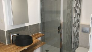 A modern bathroom with a glass shower enclosure, a wooden vanity with a black sink, and a toilet. - T2 30 M² 4 Sleeps max close to shops and 4-way access (Guignen)