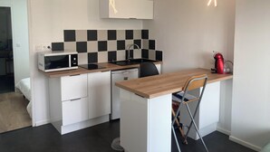 A compact kitchen with a microwave, sink, and a red kettle. - T2 30 M² 4 Sleeps max close to shops and 4-way access (Guignen)