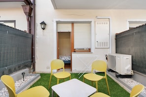 A small outdoor seating area with yellow chairs and a table, a window with blinds, a radiator, and a portable air conditioner. - Honey Home Apartment with Mountain View, Wi-Fi and Parking (San Giacomo)