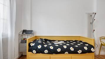 Ein Bett mit schwarz-weiß gestreifter Bettdecke, ein Nachttisch mit Lampe und ein Heizkörper.