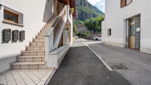 Une rue étroite avec un escalier menant à un immeuble doté d’un balcon en bois.