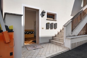 A residential entrance with a tiled floor, a wooden door, a small window, and a staircase.