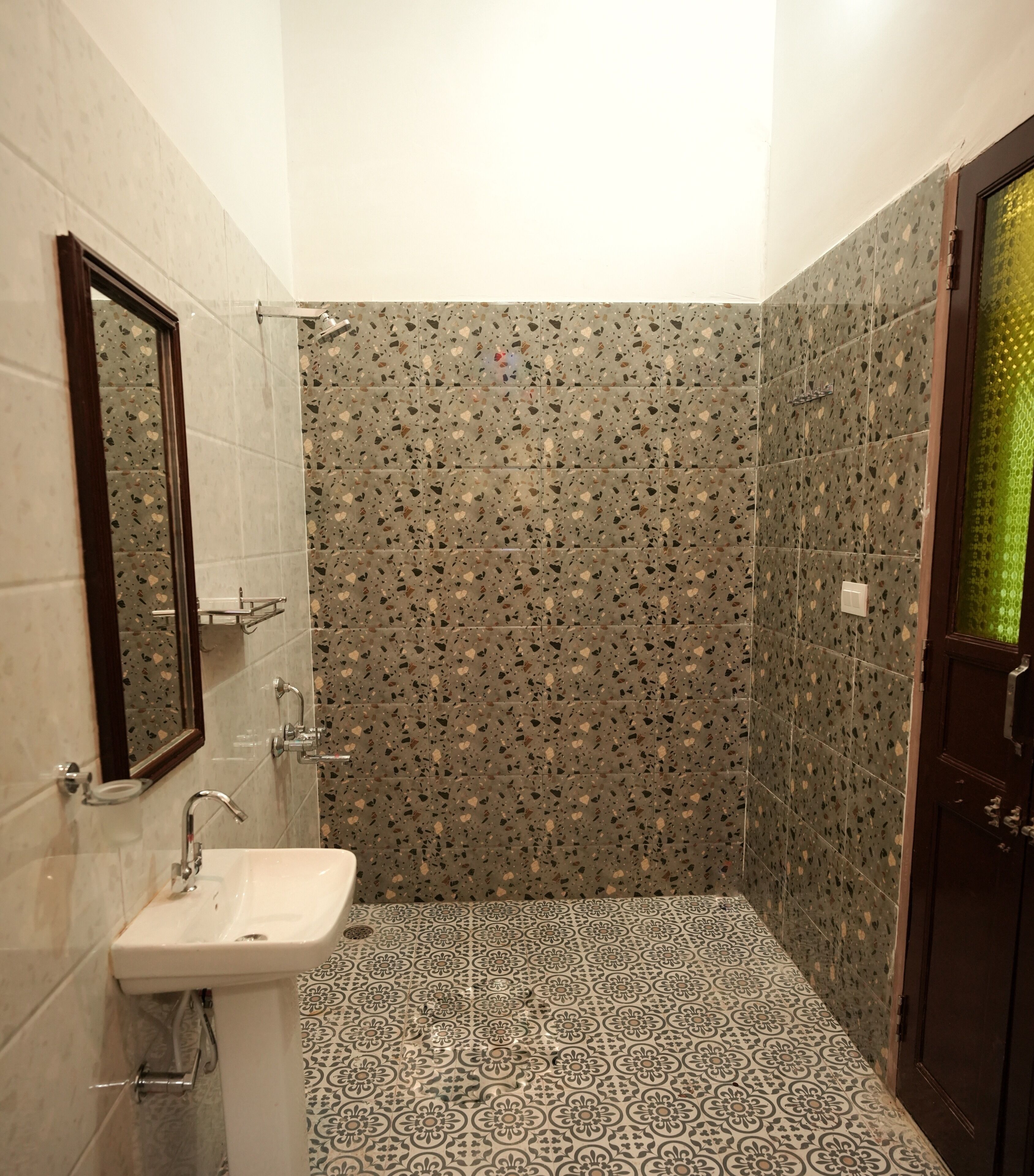 A bathroom with a sink, mirror, shower, and patterned tiles.