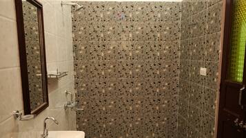 A bathroom with a sink, mirror, shower, and patterned tiles.