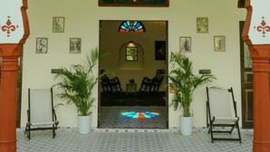 A traditional entrance with an archway, a seating area with chairs, and potted plants. - kushal niwas (Bassi)
