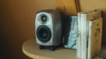 A Genlec speaker on a wooden shelf with books.