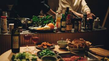 Una mesa de comedor con varios platos, botellas y vasos, mostrando una preparación para una comida.