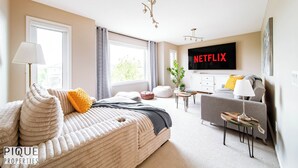 Ein modernes Schlafzimmer mit Bett, Fernseher und Sofa.