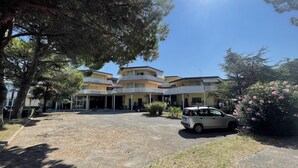 A multi-story building with a central courtyard, surrounded by trees and a parked car. - Cozy Flat in Thermal Area (San Michele al Tagliamento)