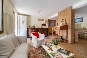 A living room with a sofa, a chair, a coffee table, and a fireplace. - 'Verde' Room with Shared Garden, Wi-Fi and Air Conditioning (Mirano)