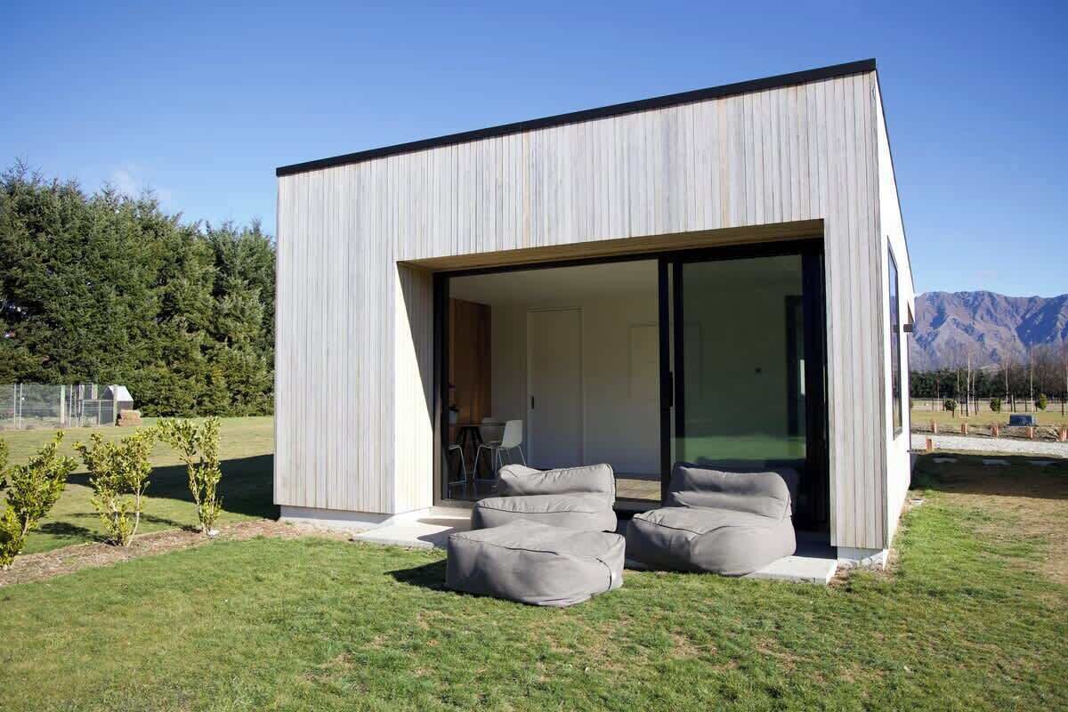 A modern house with a large glass door leading to an open patio area with outdoor seating.