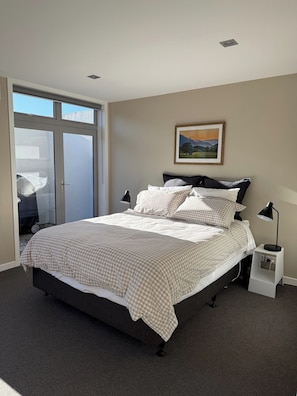A bedroom with a bed, a nightstand, a lamp, and a window with a view.