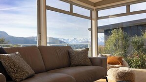 A modern living room with a large window offering a mountain view. - Alpine Lake Home Summ (Kawarau Falls)