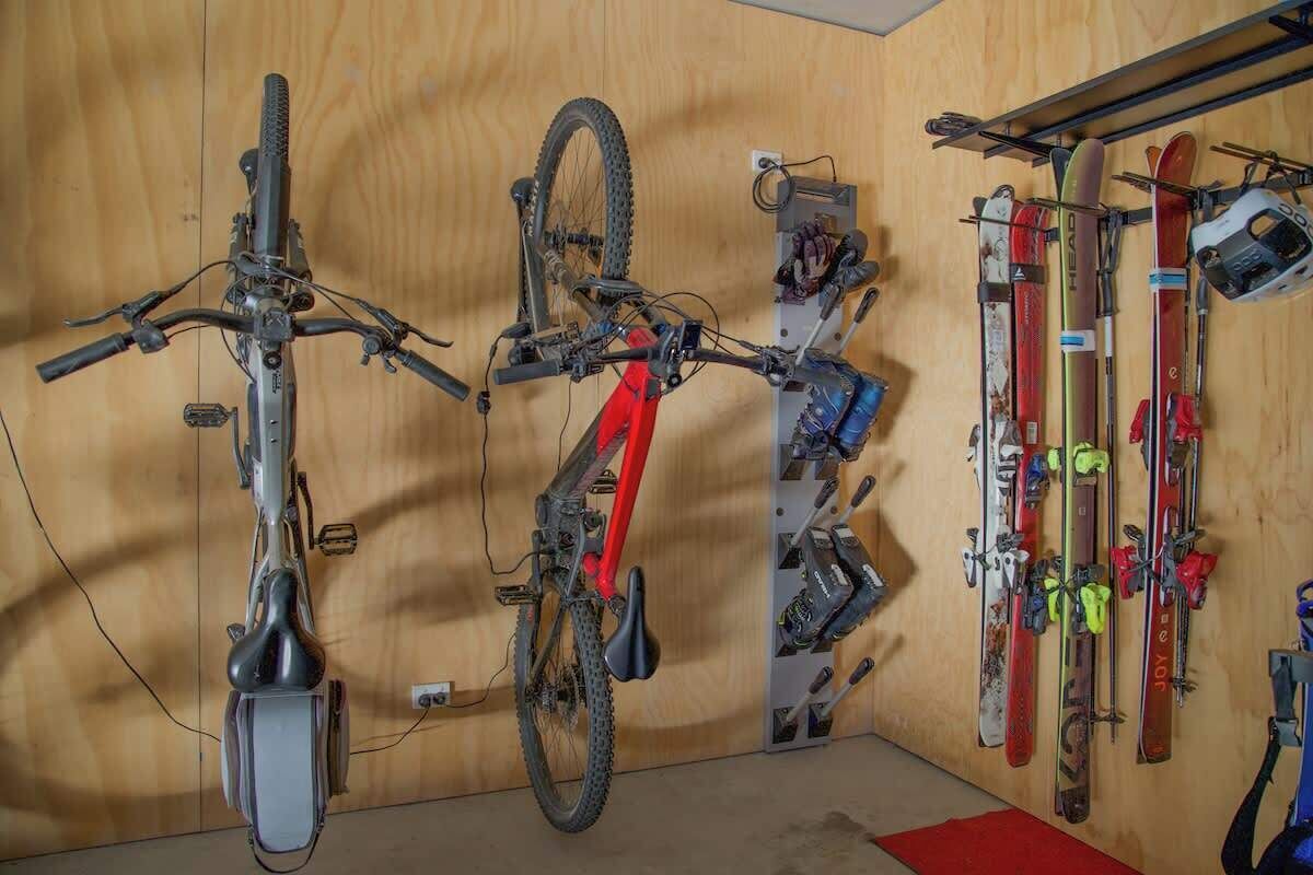 A room with a wooden wall, a bicycle, and a ski rack with skis and ski poles.